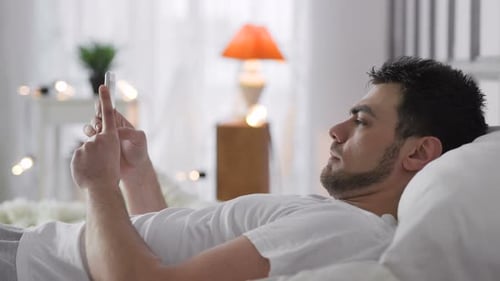 Man Lying in Bed Using Mobile Phone