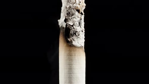 A close-up timelapse shot of a smoldering cigarette, as the camera follows the burn downward