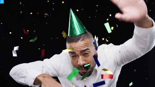 Birthday man, party hat and confetti while dancing with a whistle for fun celebration on a black