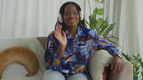 Smiling Woman in Headphones Seated on Couch