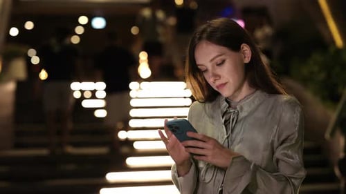 Woman Using Smartphone at Night in Urban Setting