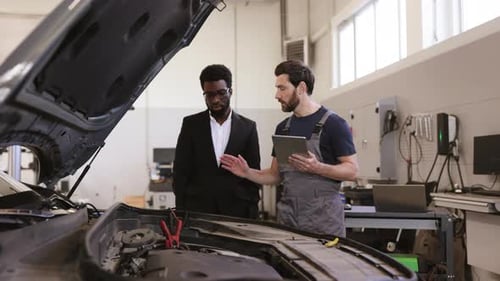 Mechanic Explaining Car Issues to Customer in Garage