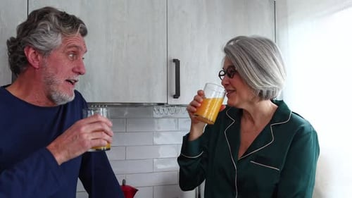 Happy senior couple enjoying morning juice together at home