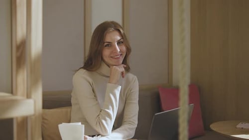 Portrait of a Beautiful Young Woman with a Laptop in a Cafe Girl Working on a Laptop in a Cozy Cafe