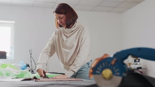 Seamstress Cutting Fabric Design Pattern in Sewing Workshop