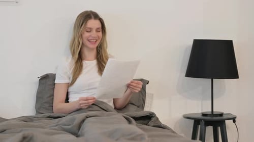 Woman Reading Documents in Bed, Happy
