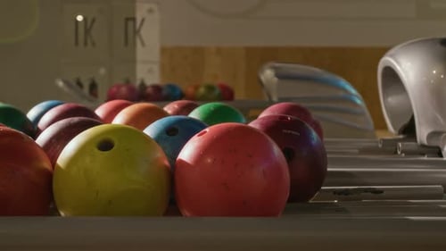 Mehrfarbige Bowlingkugeln, die im Sportclub auf der Rückgabemaschine ruhen
