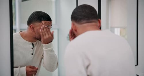 Schönheit, Hautpflege und Mann vor dem Spiegel zu Hause zur Pflege, zum Berühren des Gesichts oder zur Dermatologie im Badezimmer