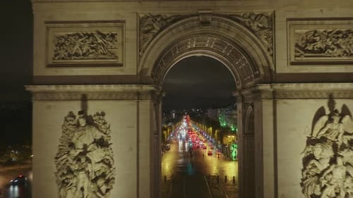 drone flies through the Arc de Triomphe in Paris at night, city lights