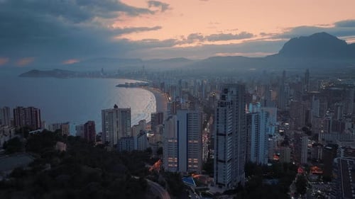 Coastal city with modern architecture next to the ocean at dusk. Golden orange sunset.