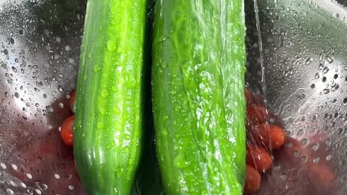 Wash cucumbers and tomatoes under running water. Slow motion
