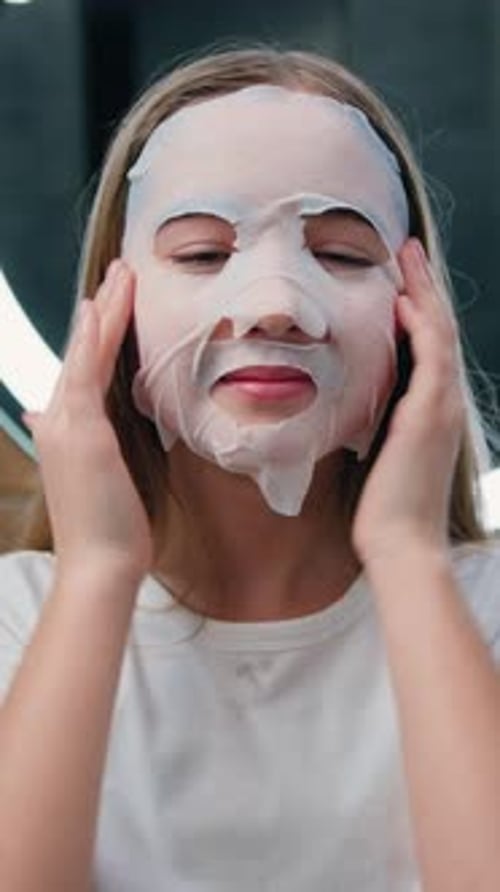 Teen Girl Applying Facial Mask in Home Bathroom