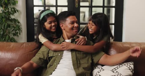 Affectionate Father Embraced by Two Smiling Daughters