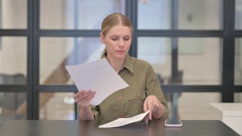 Worried Woman Looks at Documents at Desk