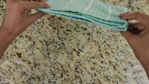 Folding green towel on marble table, top down view