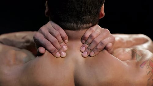 Muscular Man Kneads His Neck and Back