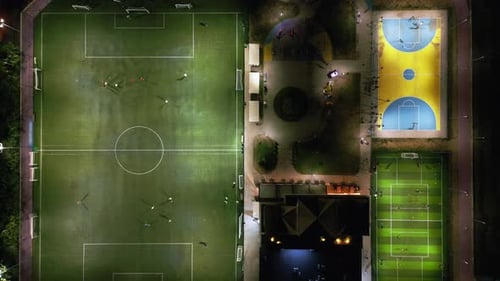 An Aerial View of an Evening Sports Ground with Soccer and Basketball Fields Where Children are