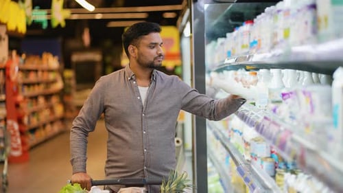 Indian Man Buying Milk in a Supermarket Dairy Aisle
