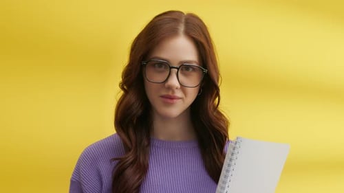 Woman with Notebook Posing in Front of Yellow Backdrop