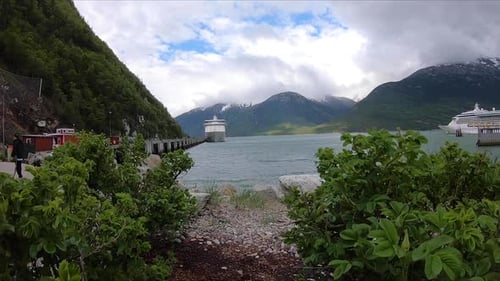 Two cruise ships are revealed to be at dock in a beautiful Alaskan bay.