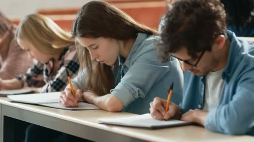 Row of Multi Ethnic Students in the Classroom Taking Exam/ Test/ Writing in Notebooks. Bright Young