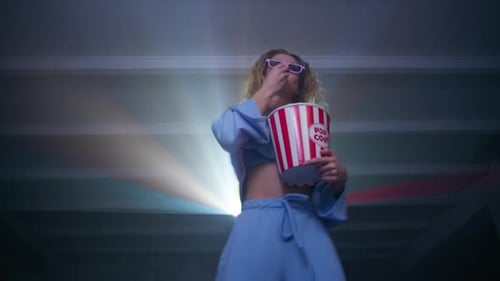 Woman Eats Popcorn in Movie Theater Setting