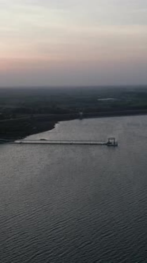 Drone survolant un grand lac avec une longue jetée à la tombée de la nuit dans les lacs de Long Thanh au Vietnam