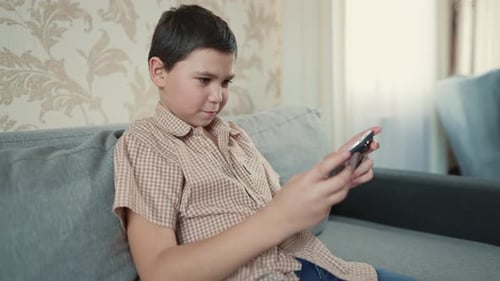 Child Plays Game on Phone Indoors at Home