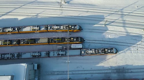 Gleitflug von oben nach unten über das Depot einer elektrischen Eisenbahn, der lange Winterschatten wirft