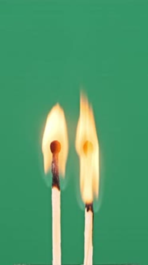 Vertical Two Match Sticks Ignites and Burns on a Green Background CloseUp
