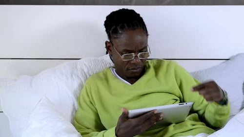 Man Relaxing in Bed Using Digital Tablet