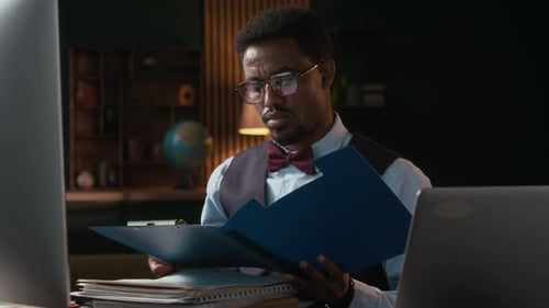 College Worker Doing Paperwork at Desk Equipped with Computer and Laptop