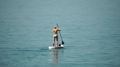 Sea Man Sup Athlete Man Floating in Calm Sea and Paddleboarding at Summer Sunset Healthy Strong Male