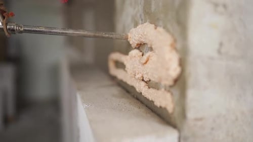 Worker Applying Expandable Foam on Brick Wall