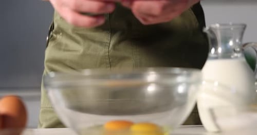 Teig machen. Mann gibt Ei und Milch in die Schüssel am Tisch drinnen, Nahaufnahme
