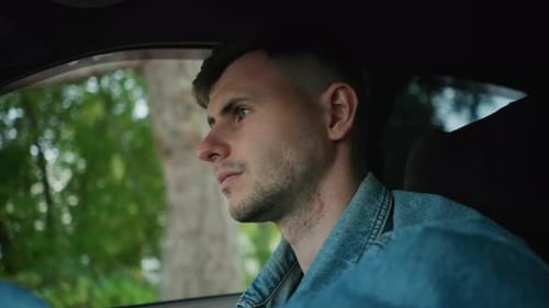Thoughtful Young Individual Navigating Car Amidst Lush Green Scenery Reflective Young Man Behind