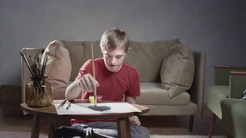 Boy Painting With Paintbrush on Floor at Home