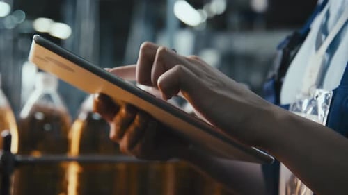 Jeune femme remplissant le protocole de qualité sur une tablette dans une usine de boissons