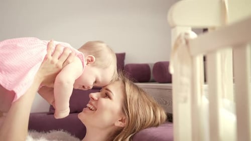 Happy Mother playing with baby in nursery room