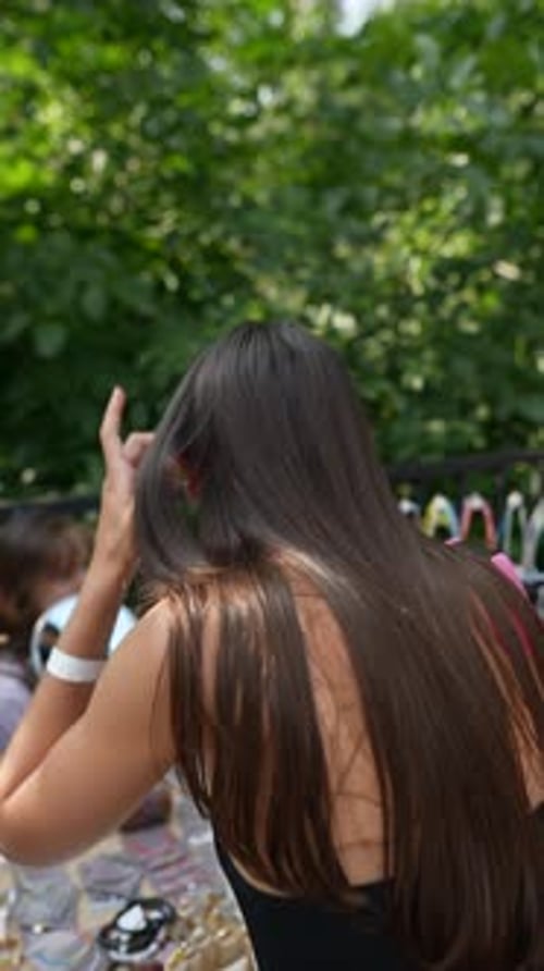 Woman Adjusts Hair at Outdoor Market