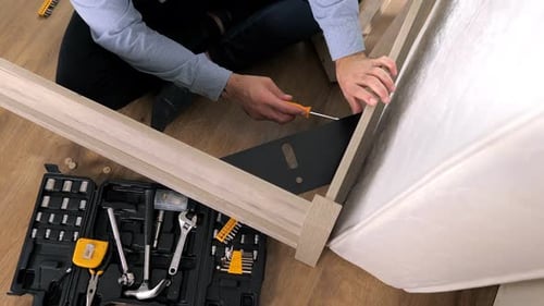 Closeup of a Man's Hand Victoriously Throws a Screwdriver After an Assembling a Wooden Bed Well Done