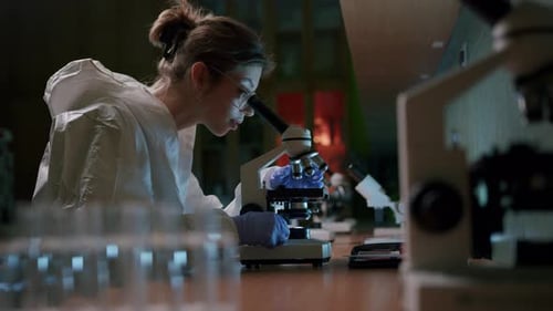 A young beautiful female scientist works with a professional microscope in the laboratory—medium sho