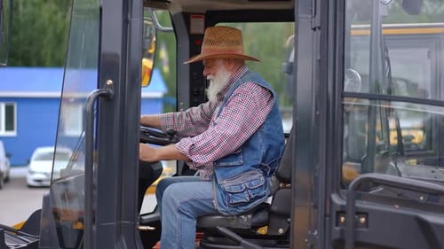 Wide Shot Side View of Happy Senior Farmer Sitting in Tractor Turning Looking at Camera Gesturing