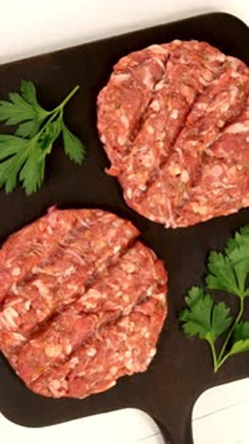 Round Fresh Raw Mince Beef Burger Cutlet Ready to Prepare Rotate on Dark Kitchen Board