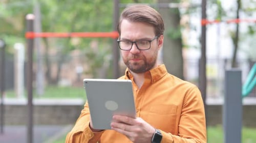 Man Celebrates Good News on Tablet Outdoors