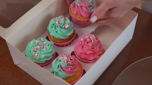 High Angle View Paper Box for Pastry Delivery and Female Caucasian Hands Placing Tasty Muffins