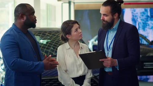Portrait of Happy Salesman Talking with Clients Showcasing Dealership Vehicle