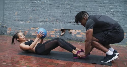 Woman Doing Sit Ups with Medicine Ball Outside