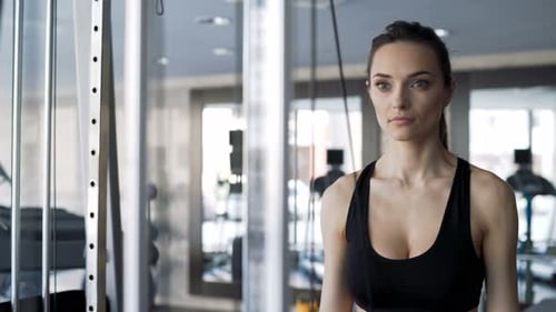 Woman Exercising Arms with Rope Pulldown Machine
