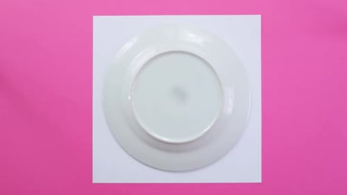 Utilisation d'une assiette en porcelaine pour dessiner la circonférence sur papier, fond rose